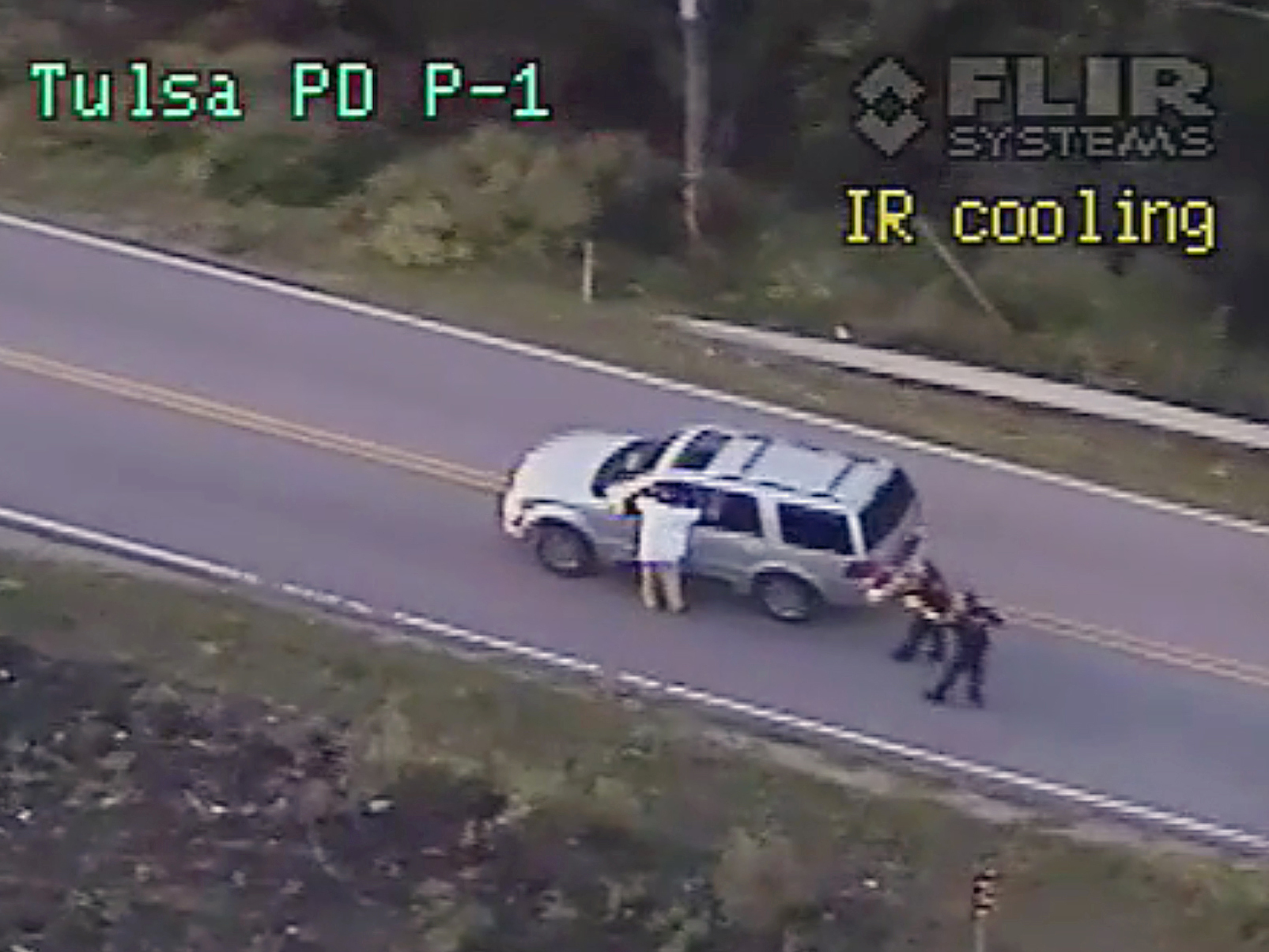 In this photo made from a Sept. 16, 2016 police video, Terence Crutcher, left, with his arms up is pursued by police officers as he walks next to his stalled SUV moments before he was shot and killed by one of the officers in Tulsa, Okla.