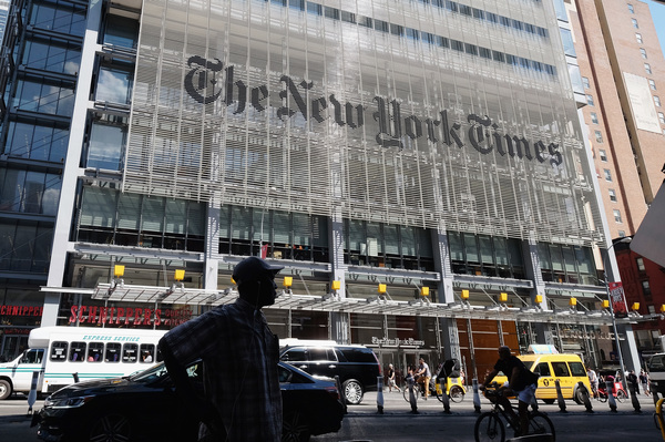 Pedestrians walk by the outside of The New York Times Building in June.