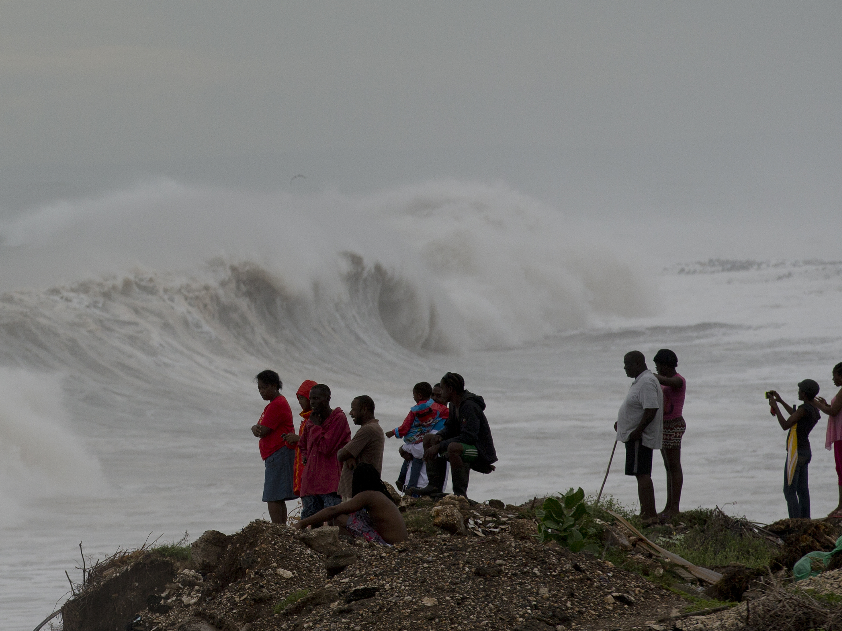 People watch waves break on the outskirts of Kingston, Jamaica, on Monday. Hurricane Matthew has generated large surf, heavy rain and wind. Eduardo Verdugo/AP.