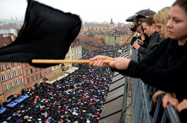 A demonstrator waves a black flag on Monday as people in Warsaw take part in a nationwide strike and demonstration to protest against a legislative proposal for a total ban of abortion in Poland.
