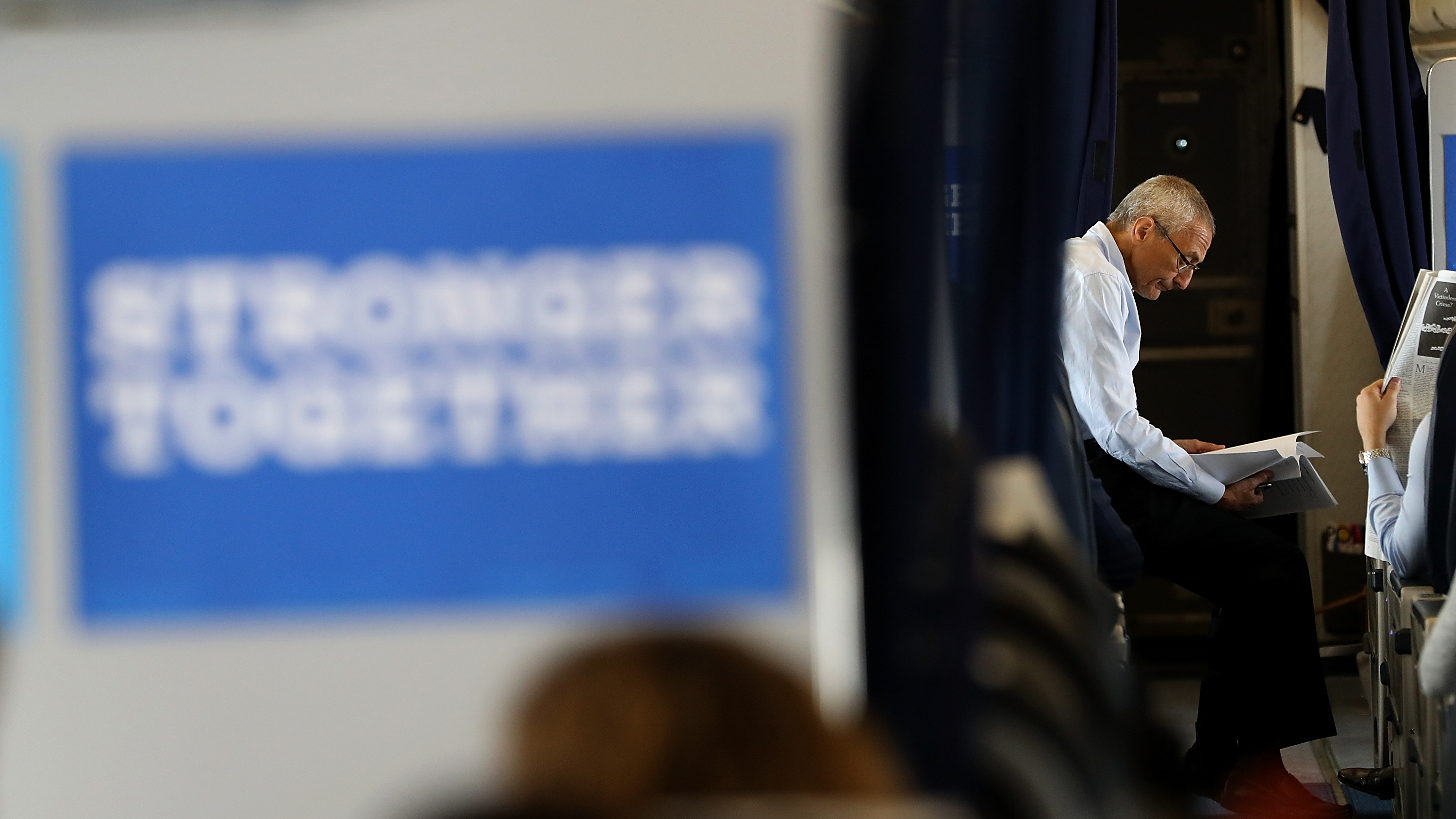 John Podesta, campaign chairman for Hillary Clinton, reads aboard the campaign plane while traveling to Raleigh Durham International Airport on Sept. 27. (Getty Images)