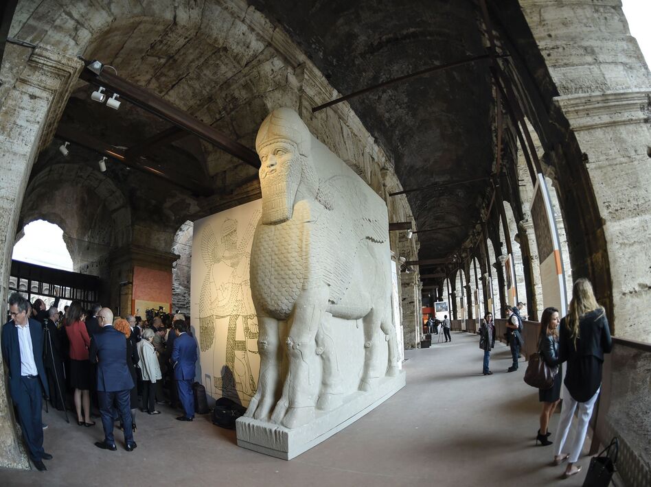 People walk past a replica of an ancient statue of a human-headed winged bull from Nimrud, Iraq, destroyed by the Islamic State. It's part of an exhibition called "Rising from Destruction" at Rome's Colosseum. (Andreas Solaro/AFP/Getty Images)