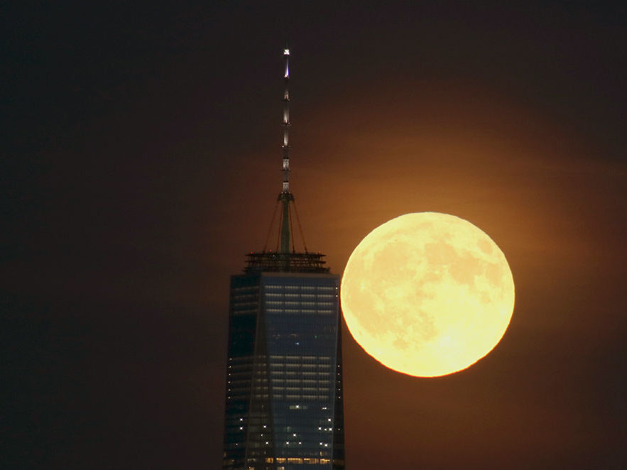 A full moon rises behind Lower Manhattan and One World Trade Center in September in New York City.