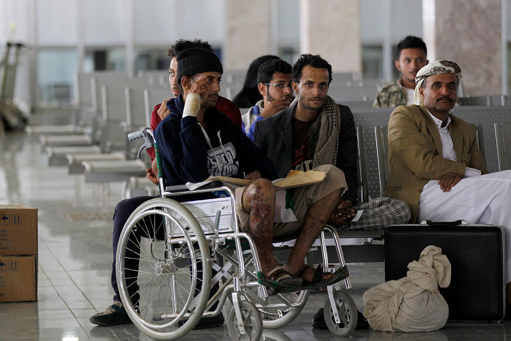 Yemeni men wounded during the airstrike at a funeral sit in the airport in Sanaa on Saturday as they wait for an Omani plane to evacuate them.