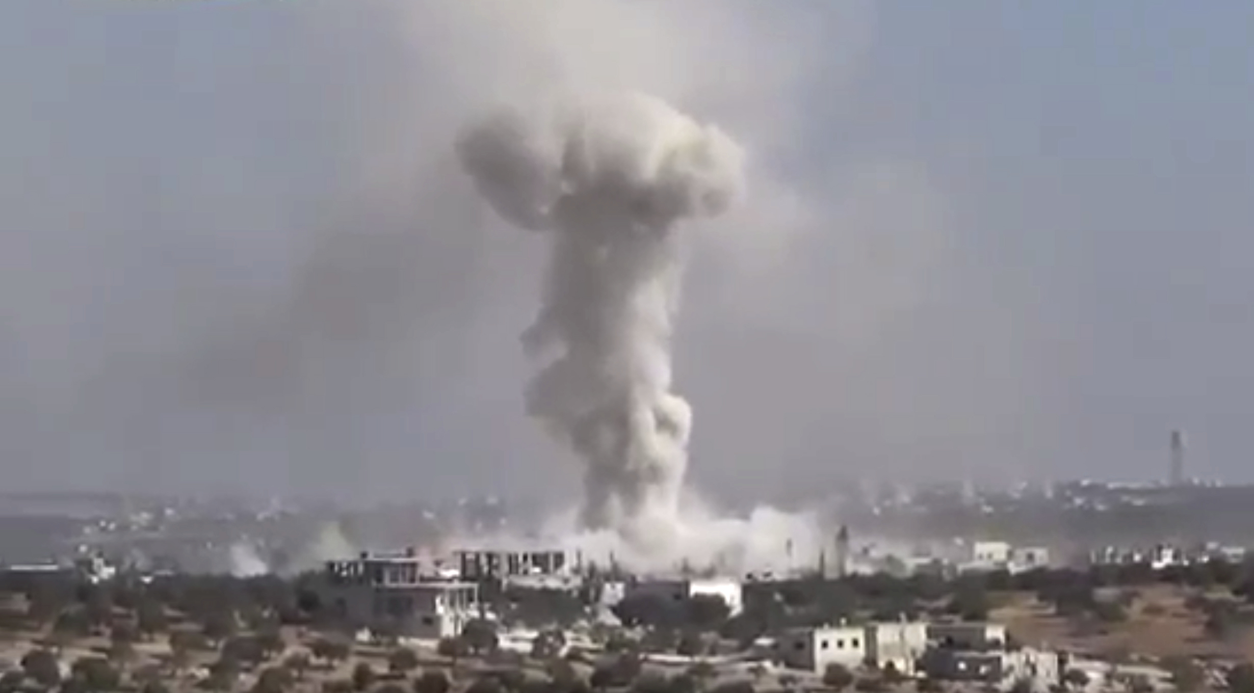 Smoke rises in the distance after an airstrike Wednesday on the village of Hass, Syria, where teachers and students were killed.