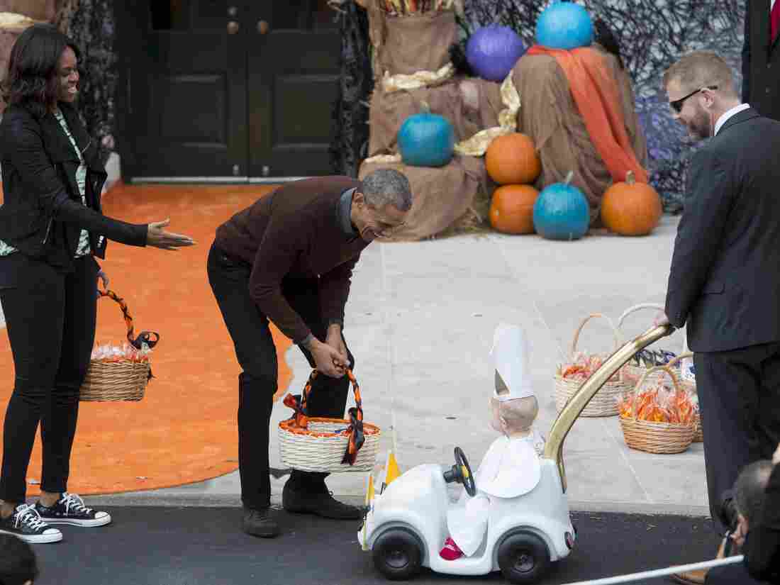 President Obama greets a baby dressed as the Pope riding in a "Popemobile."