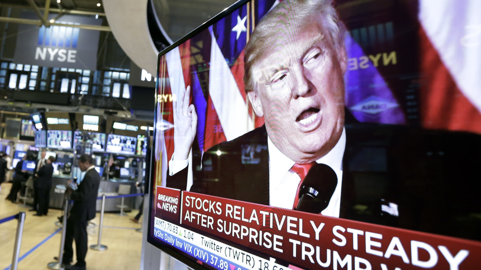 An image of President-elect Donald Trump appears Wednesday on a television screen on the floor of the New York Stock Exchange. Business leaders are taking a wait-and-see approach to his administration. (Richard Drew/AP)