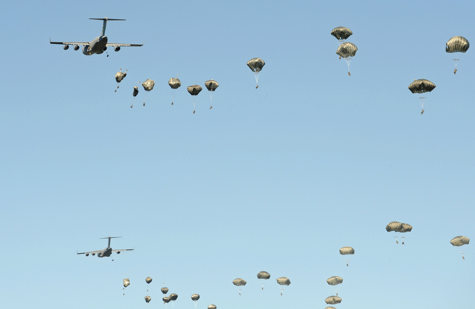 U.S. military planes drop paratroopers during a multi-national jump that includes soldiers from the U.S., Britain and Poland on June 7, near Torum, Poland. U.S. President-elect Donald Trump has questioned the value of the NATO alliances, raising worries among many European countries. (Alik Keplicz/AP)