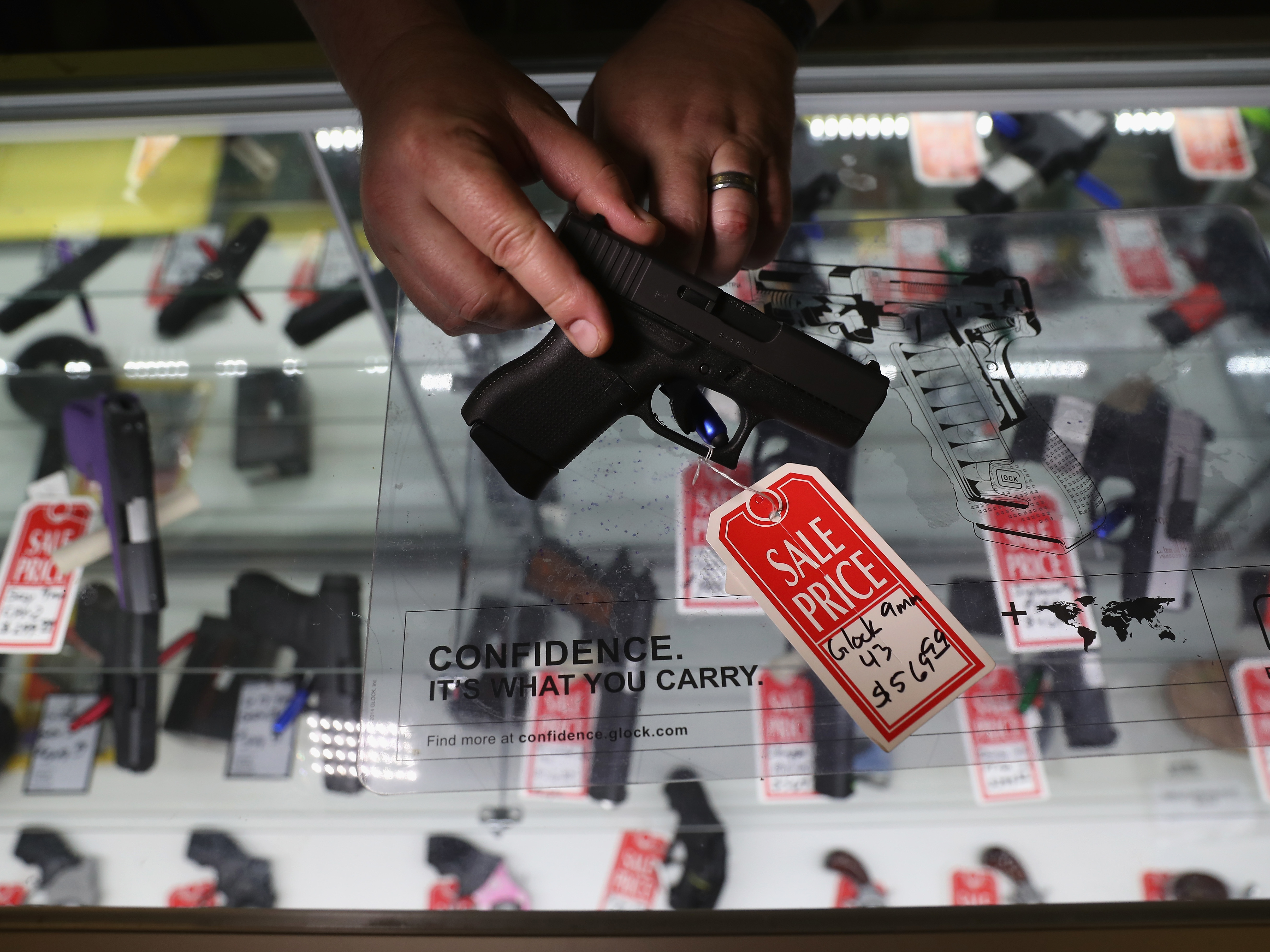 Gun shop owner Jeff Binkley displays a Glock 9mm pistol at Sarge's Sidearms in Benson, Ariz., in September.