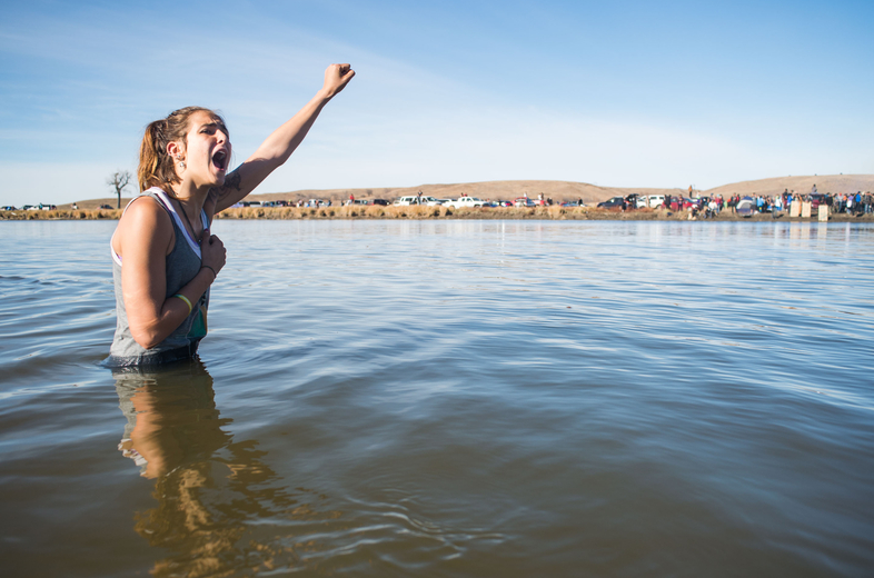 Demonstrator Stephanie Jasper stands in the Cannonball River during a standoff with police at Turtle Island, north of the Standing Rock Sioux Reservation. (Emily Kask for NPR)