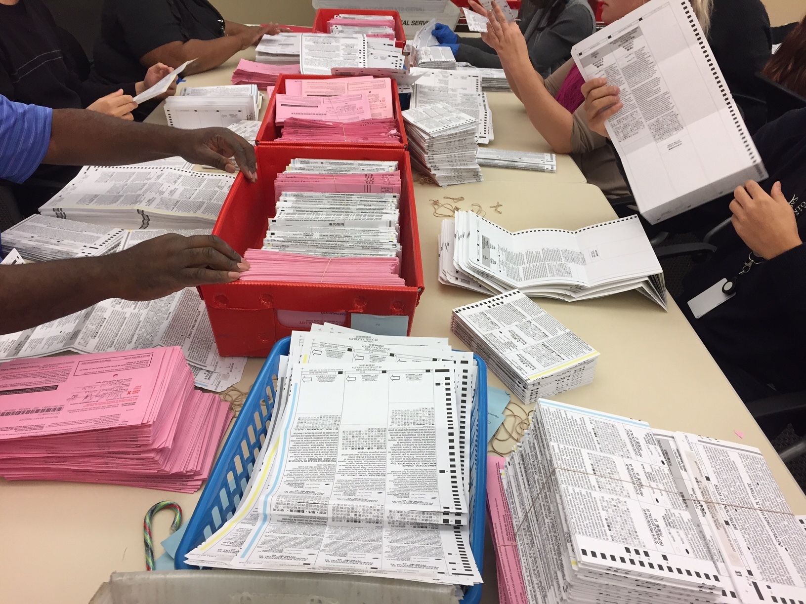 Election workers sort through unprocessed vote-by-mail ballots at the Sacramento County Registrar of Voters office on Monday. (Capital Public Radio)