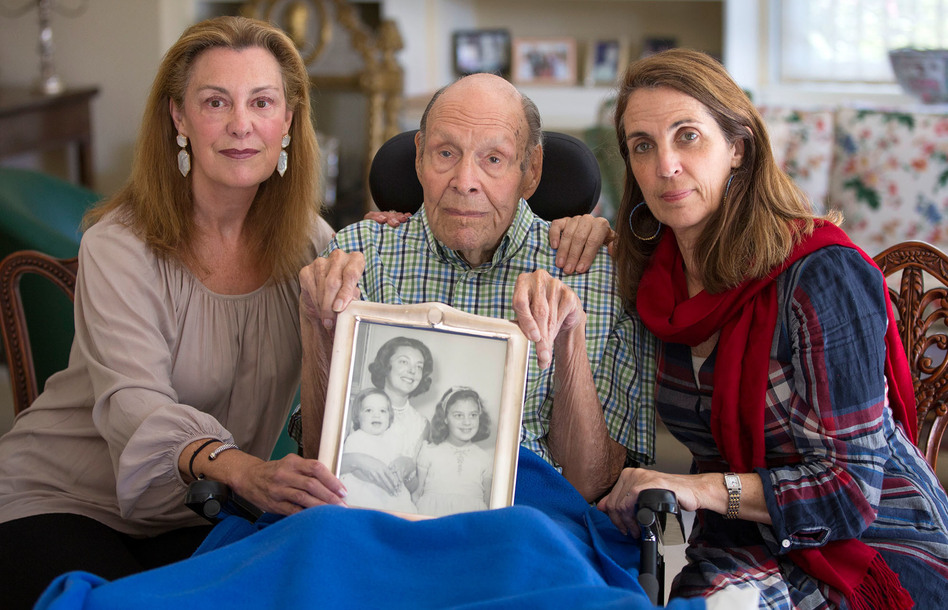 Laura Rees (left) and her sister Nancy Fee sit with their father, Joseph Fee, while holding a photo of his late wife, Elizabeth. (Robert Durell for KHN)
