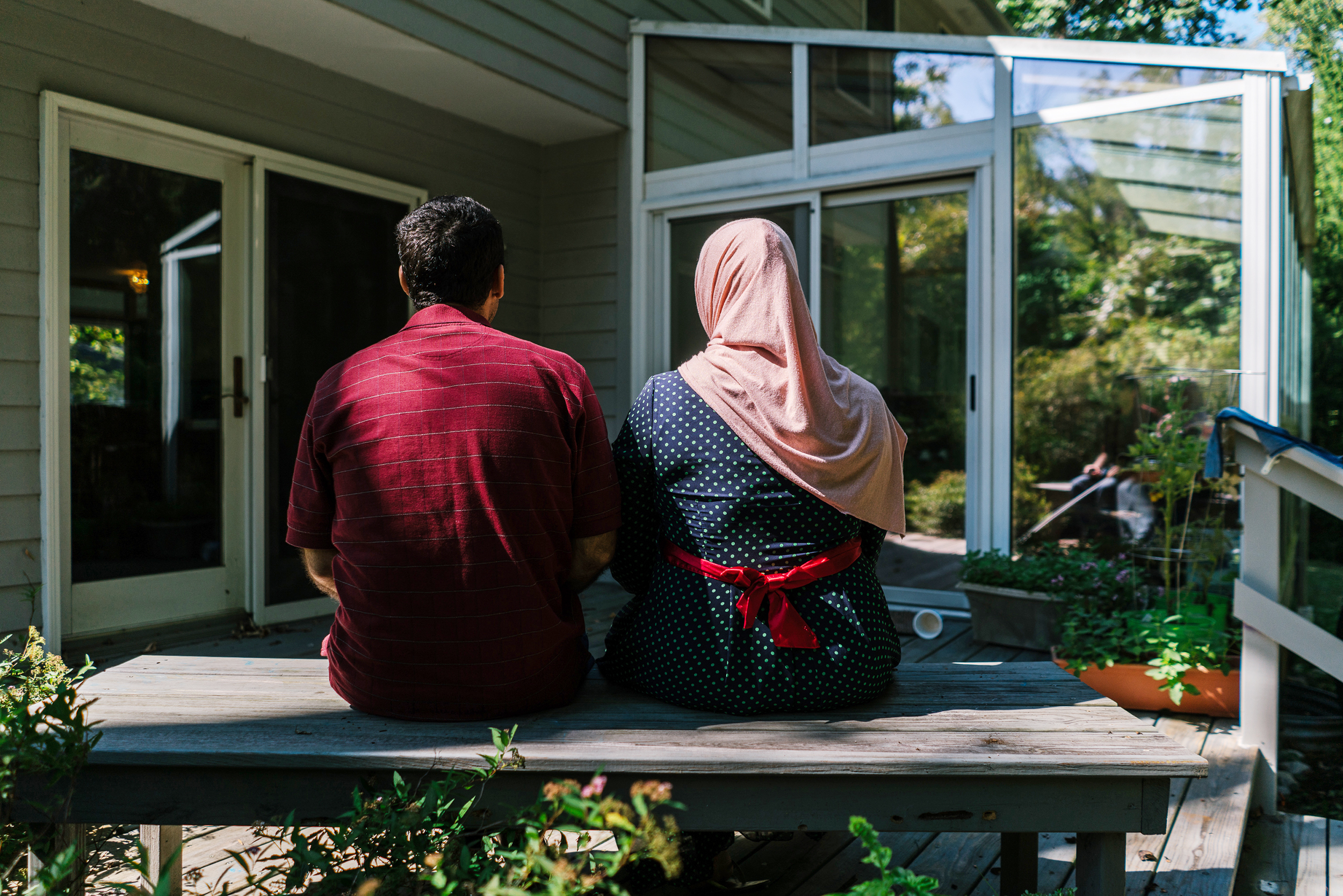 Osama and Ghada sit on the deck of their home in Princeton, N.J. They and their children are refugees from Syria and have been resettled with help from the Nassau Presbyterian Church. (Jake Naughton for NPR)