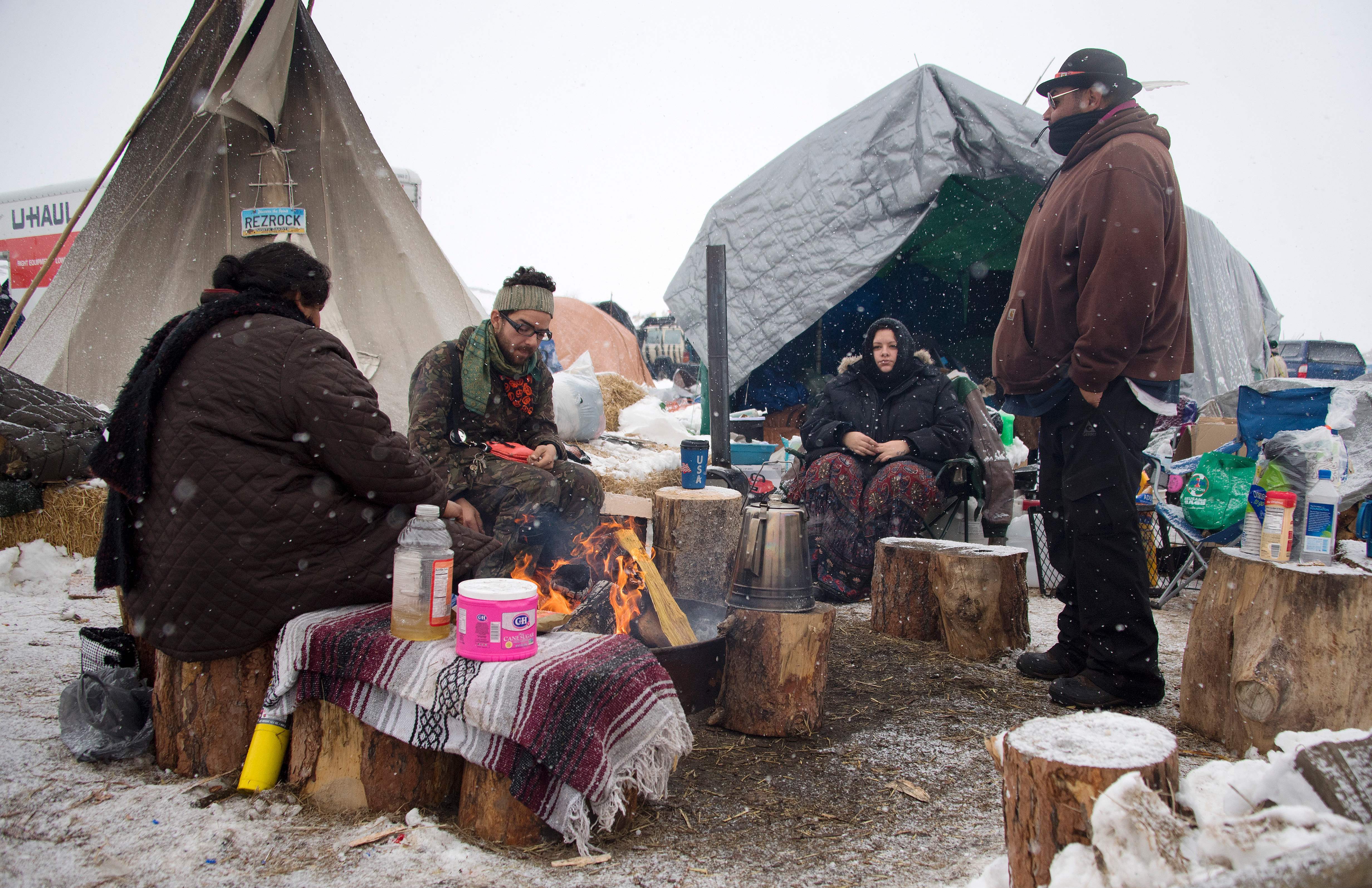 Protesters sit around a campfire as it snows at Oceti Sakowin camp on Monday. Jim Watson/AFP/Getty Images