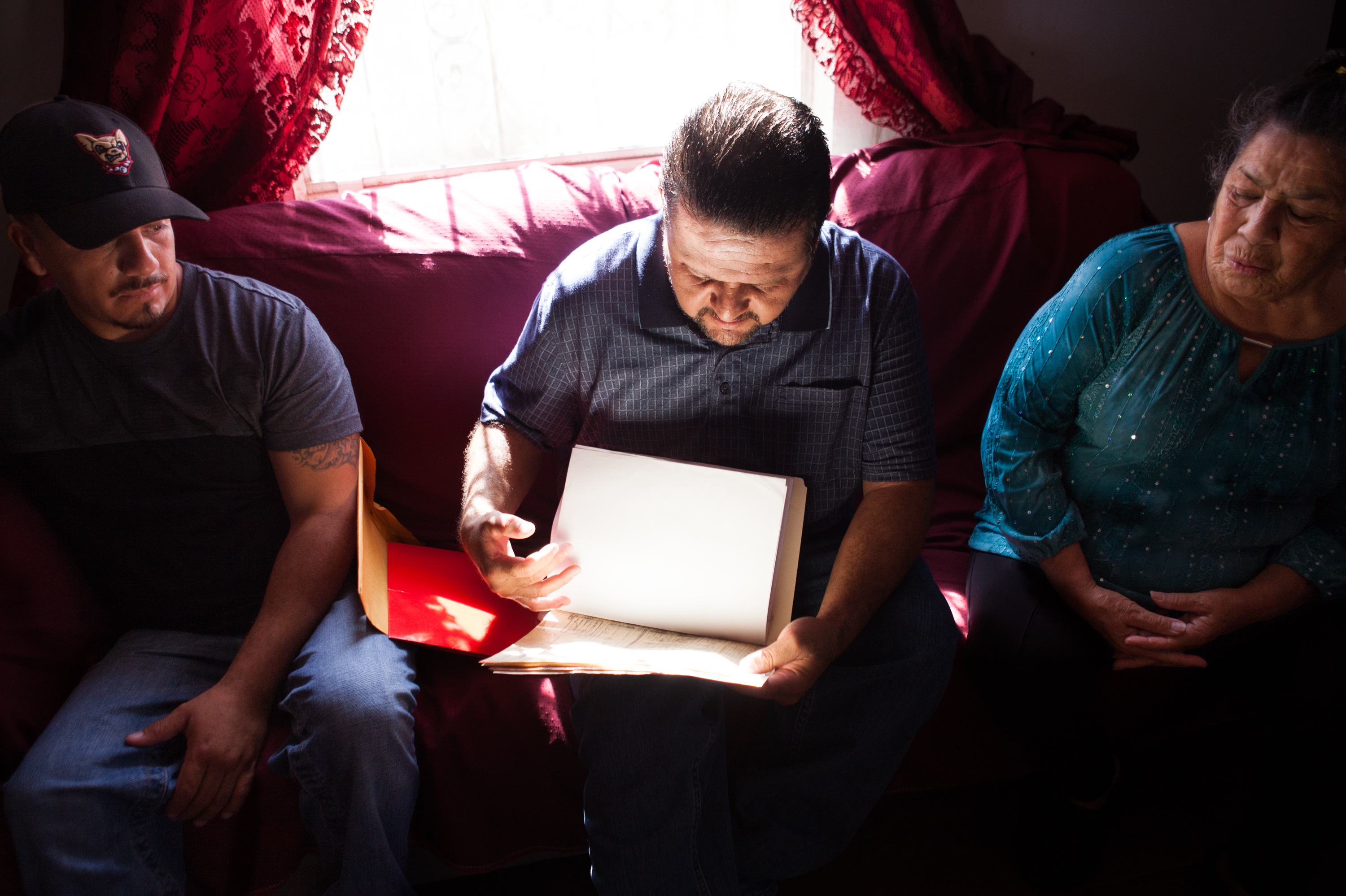 Lorenzo Palma (center) reviews family documents with his brother and mother in their home in El Paso, Texas. Palma served time for a parole violation and, just as he was being released, was sent before an immigration court to prove his U.S. citizenship. (Bree Lamb for NPR)