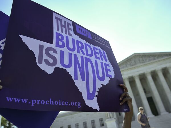 An abortion rights activist holds a sign outside the U.S. Supreme Court earlier this year before the court struck down a Texas law placing restrictions on abortions. Now abortion rights supporters are suing the state again over a new rule.