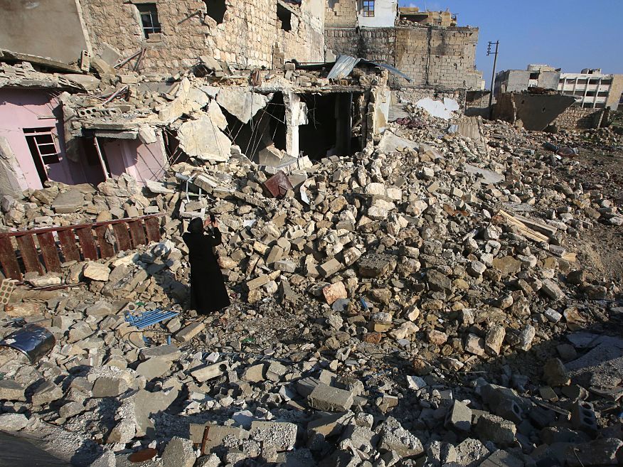 Kefa Jawish takes pictures of the rubble as she heads with her husband to check their house for the first time in four years in Aleppo's northeastern Haydariya neighborhood on Dec. 4. (AFP/Getty Images)