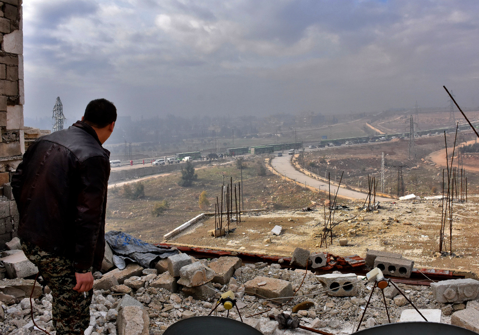 A member of the Syrian government forces watches during an evacuation of Syrian rebel fighters and civilians from a opposition-held area of Aleppo on Friday. (George Ourfalia/AFP/Getty Images)