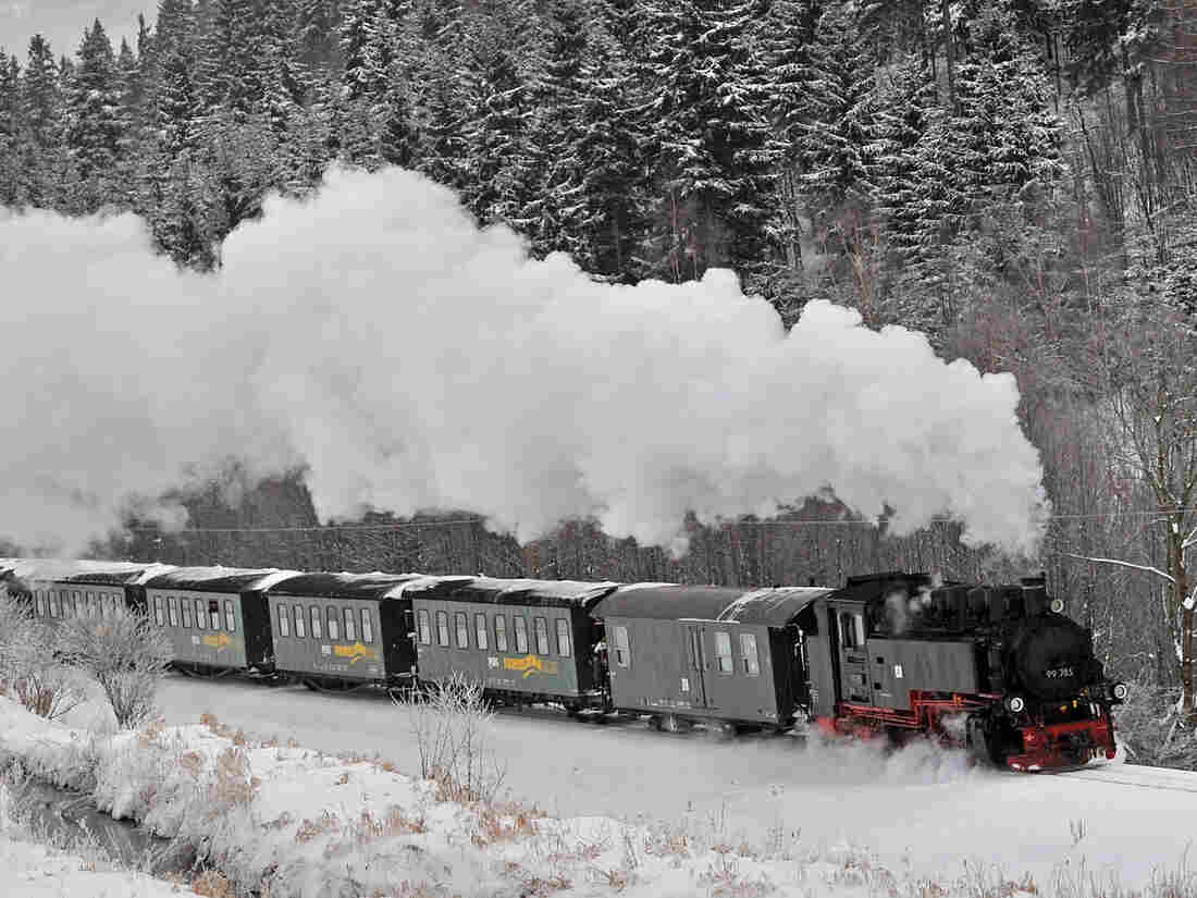 A steam engine makes its way through a snow-covered landscape.