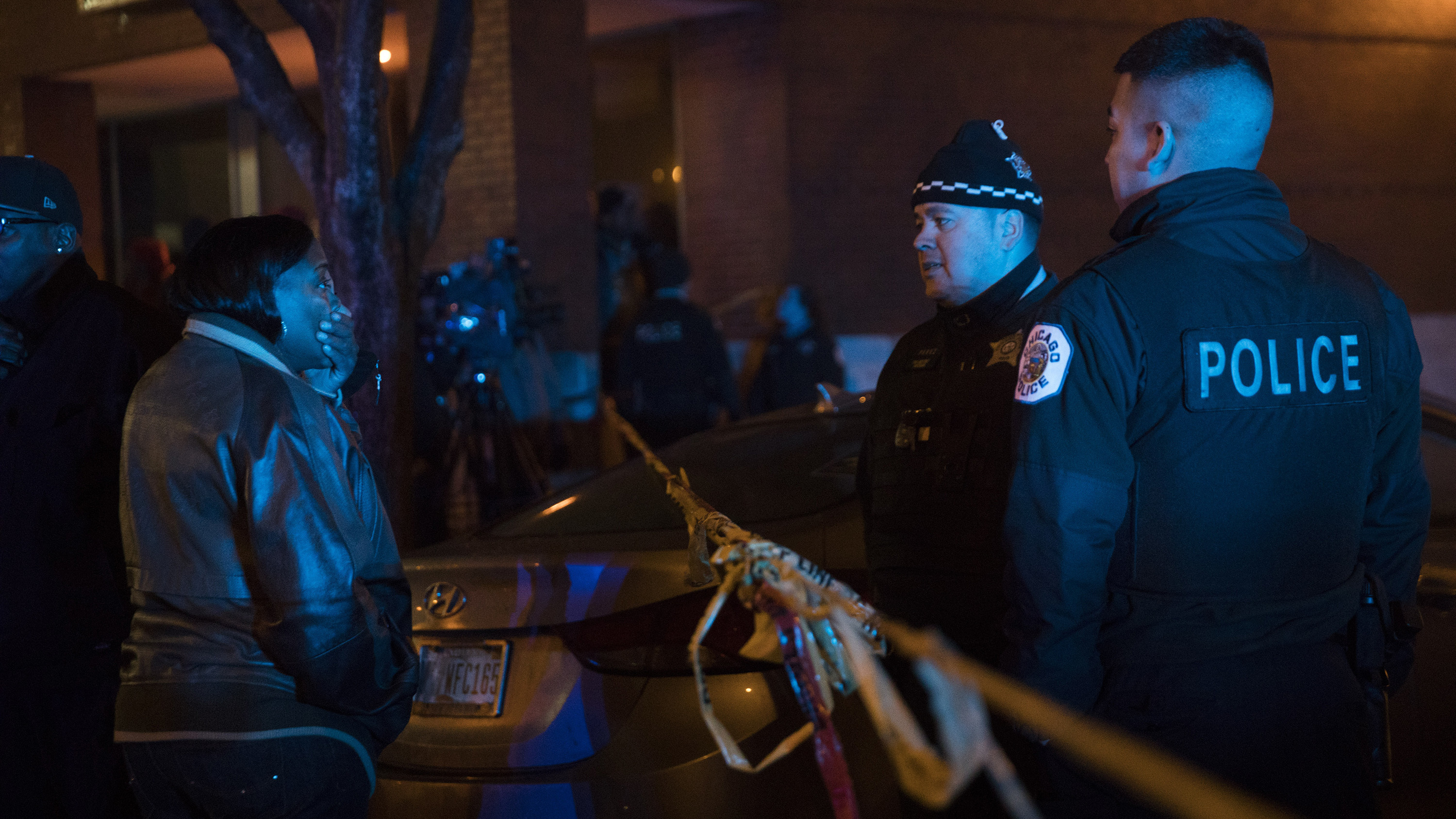 A woman talks with members of the Chicago Police Department at the scene where at least six people were shot on Sunday. Dozens of people were shot over the holiday weekend in Chicago. (TNS via Getty Images)