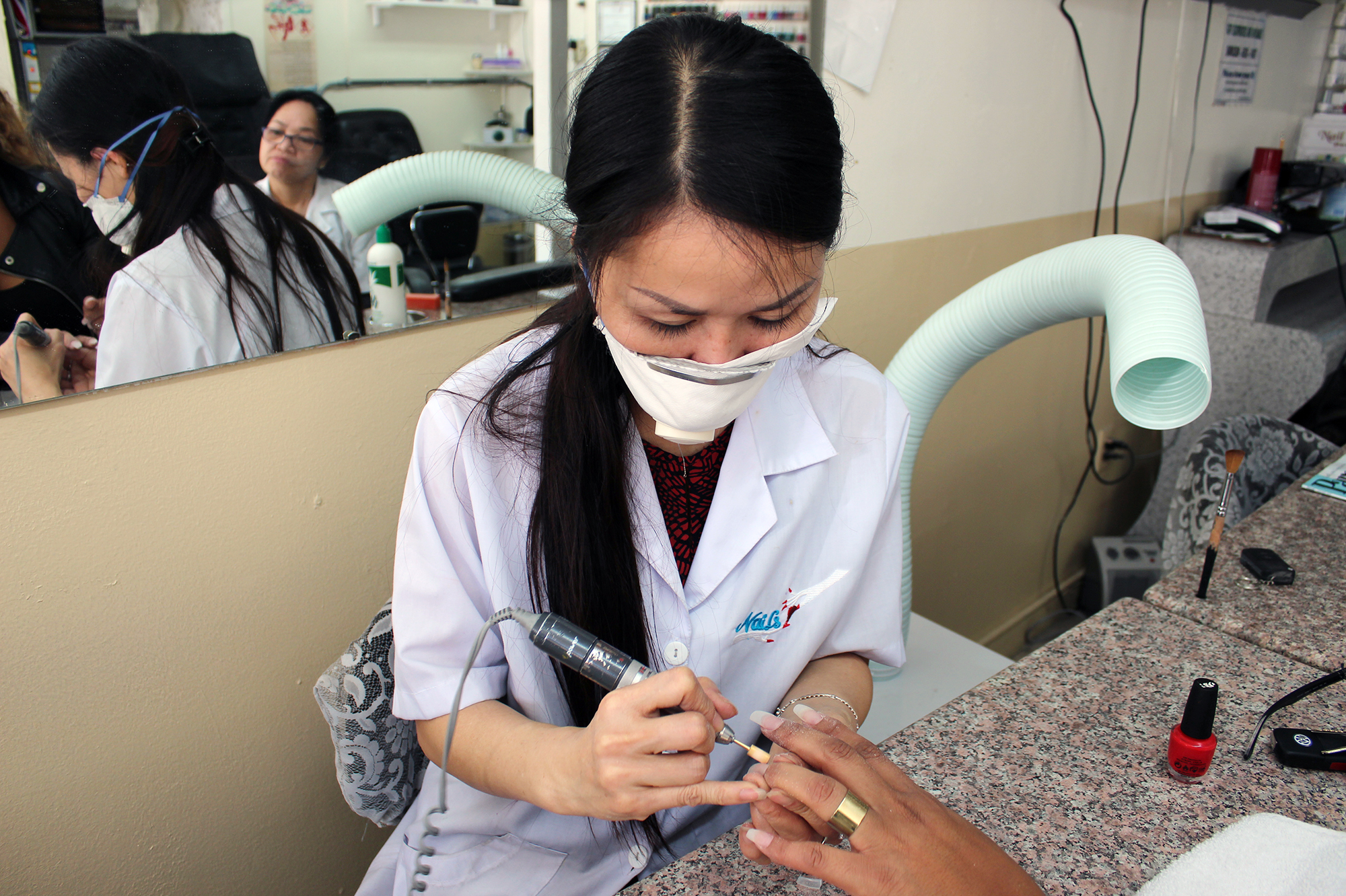 Mai Dang, who owns Fashion Nails in Berkeley, Calif., does a client's nails. The ventilator hose poised over her shoulder helps keeps noxious fumes at bay. (Jenny Gold/Kaiser Health News)