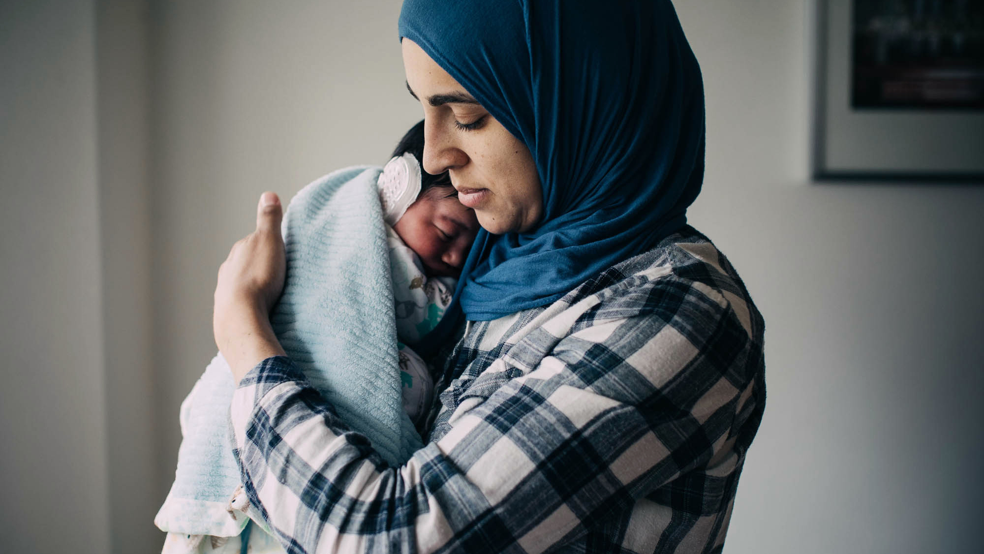 Salma Shabaik holds her newborn son, Ali. When he was born, she held him naked against her bare skin, a practice called kangaroo care. Ali is wearing an ear cap to correct a lop ear.