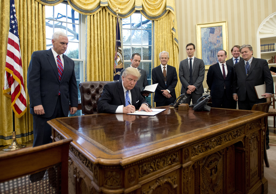 President Trump signs the executive orders in the Oval Office on Monday, including a withdrawal from the Trans-Pacific Partnership trade deal. (Ron Sachs/Pool/Getty Images)