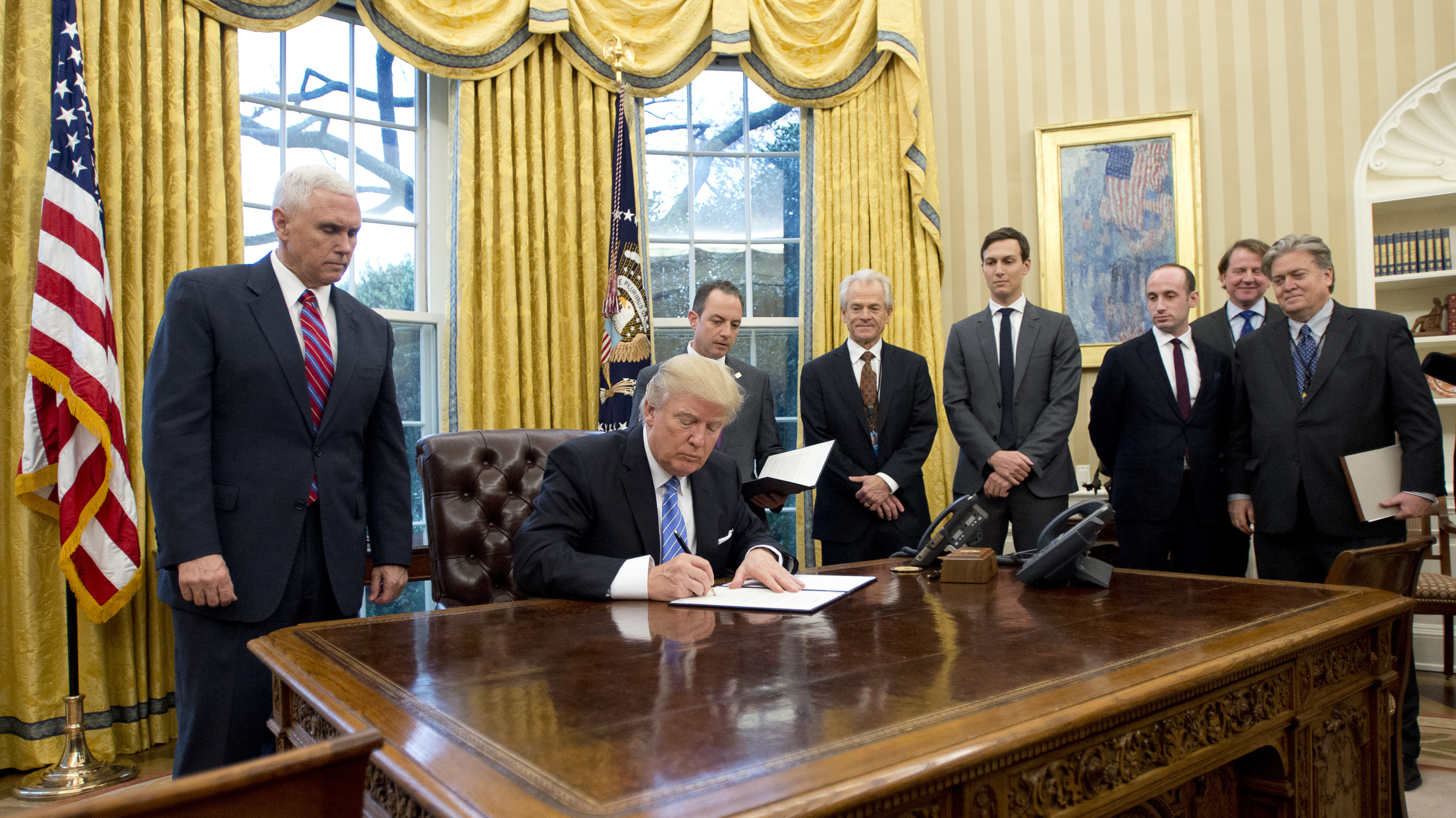 President Trump signs the executive orders in the Oval Office on Monday, including a withdrawal from the Trans-Pacific Partnership trade deal.