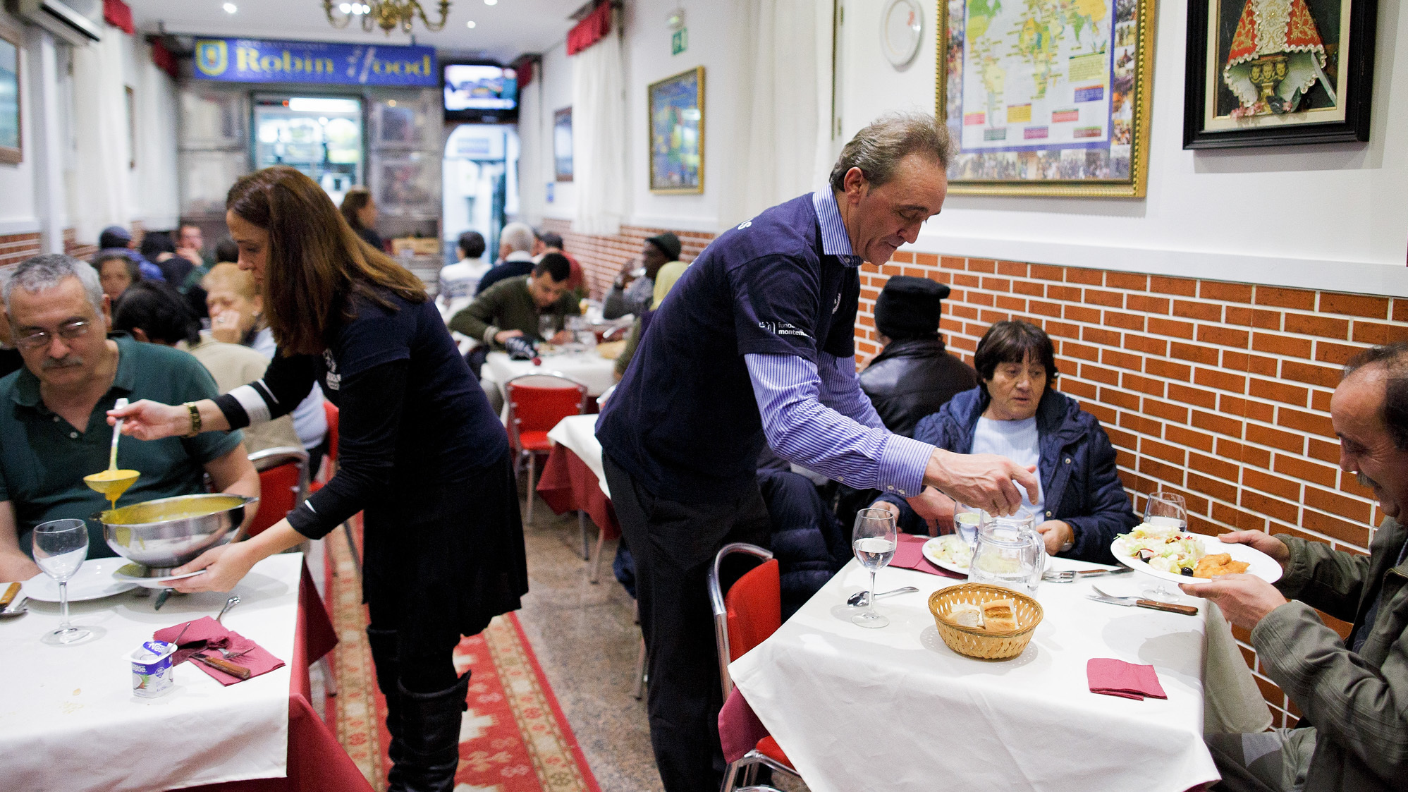 Volunteers serve free dinner to homeless people at Robin Hood restaurant in Madrid.