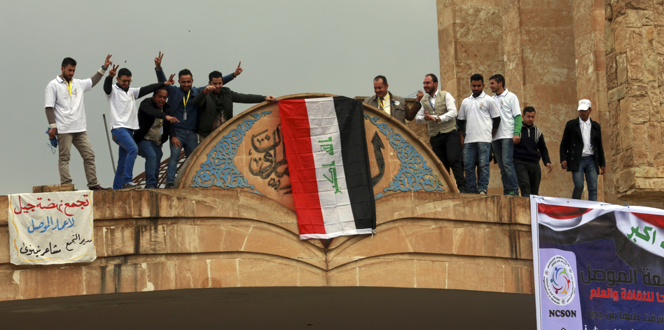 Students at Mosul University place the Iraqi national flag at the entrance on Sunday after it was liberated from Islamic State militants. The Iraqi military, supported by the U.S., has retaken the eastern part of the city. ISIS still holds the western part of Mosul, its last major stronghold in Iraq. (Khalid Mohammed/AP)