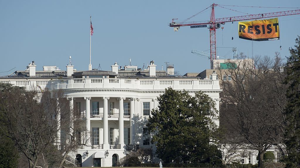 Greenpeace protesters unfold a banner reading "Resist" from atop a construction crane on Wednesday behind the White House.