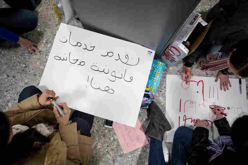 Volunteers pen signs in Arabic with messages indicating "free legal help" available for arrivals at Washington Dulles International Airport in D.C.