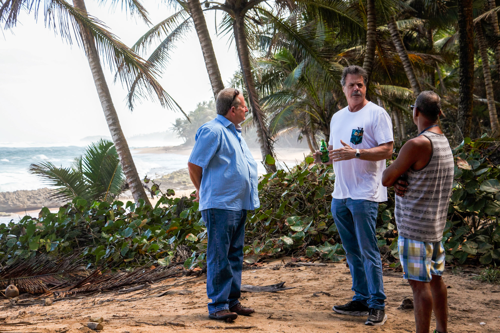 Mike McCloskey, his cousin Manuel Perez (left), and one of their co-workers on a beach at the edge of their new farm in Puerto Rico. McCloskey and Perez played on this beach as children. (Dan Charles/NPR)