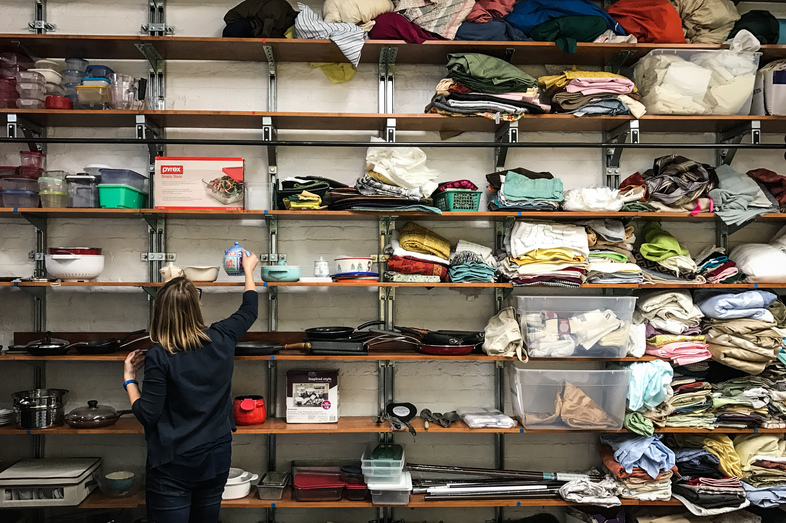 Betsy Jenson sorts through donated kitchenware, bed sheets and other household goods inside a storage area for the Nationalities Service Center in Philadelphia. The refugee resettlement agency uses donations to furnish apartments for newly arrived refugees. (Hansi Lo Wang/NPR)