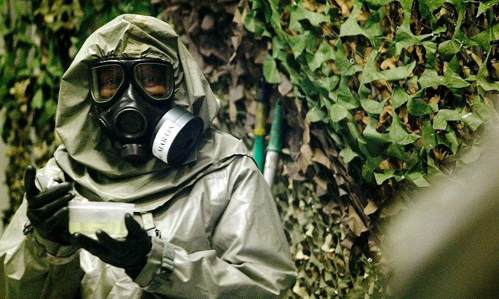 An instructor at Fort Leonard Wood, Mo., carries VX nerve agent inside a special chamber used for training in 2003. (Getty Images)