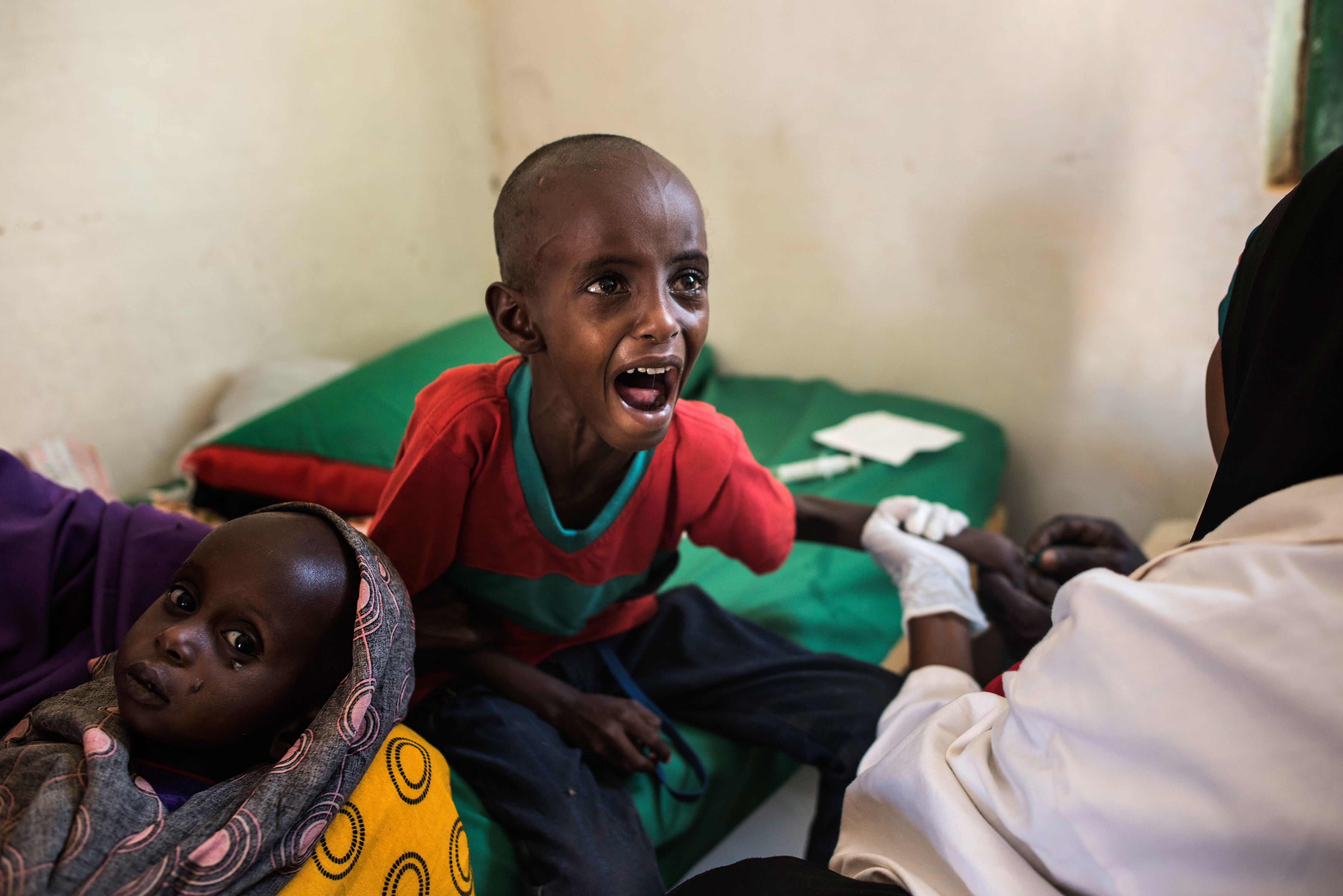 A 5-year-old child cries as a nurse struggles to find a vein for an injection at a health clinic last month in Shada, Somalia. The child's family lost all their animals to drought and traveled more than 100 miles in search of a better situation. (Getty Images)