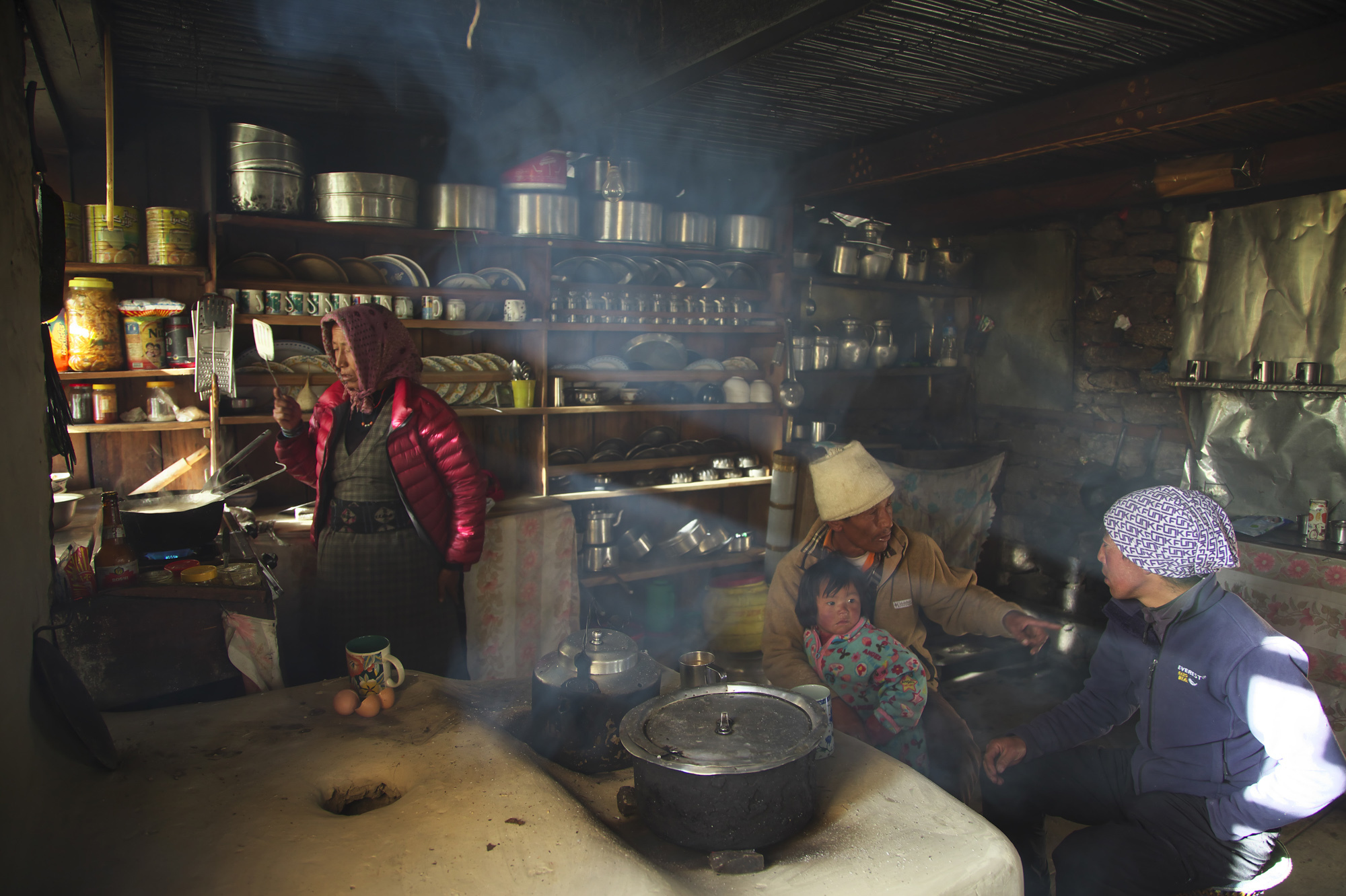 A family in Nepal prepares a meal. The use of organic fuels like wood or animal dung for cooking contributes to indoor air pollution.