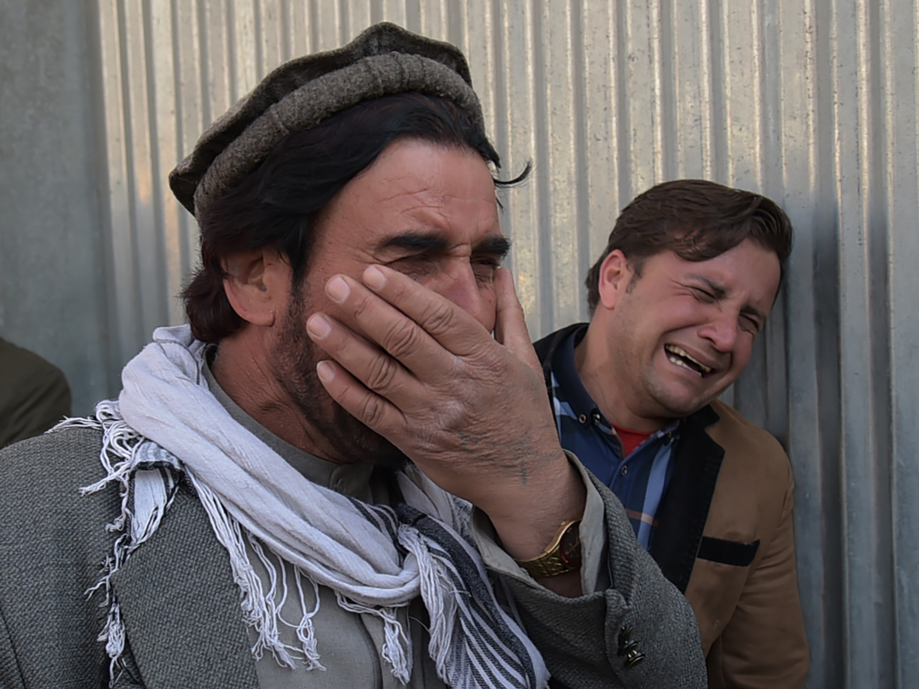 Two Afghan men weep for their relatives in front of the main gate of a Kabul military hospital Wednesday, after a deadly six-hour attack claimed by the Islamic State. (AFP/Getty Images)