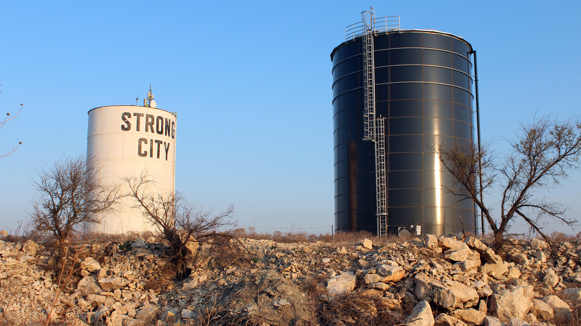 A new water tank in Strong City, Kan., (at right) sits next to one that was part of an old leaky system on a hill just outside the city limits. (KCUR)