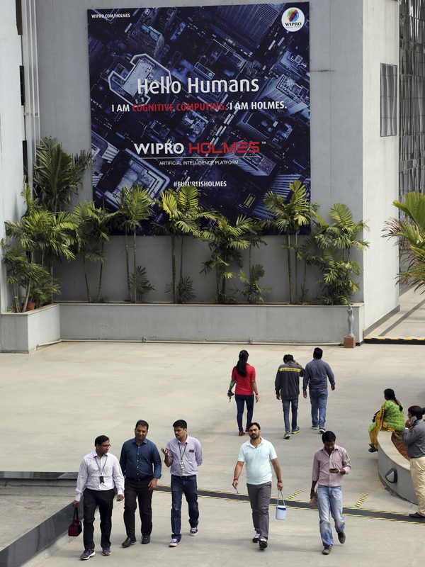 Wipro Ltd. employees walk inside the company's compound in January during a break at their headquarters in Bangalore, India. Top Indian IT companies are in the crosshairs of proposed changes to U.S. H-1B visas, including an executive order President Trump is expected to sign Tuesday.