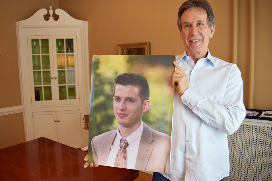 Dr. James Baker holds a photo of his son, Max, who had been sober for more than a year and was in college when he relapsed after surgery and died of a heroin overdose. (Craig LeMoult/WGBH)