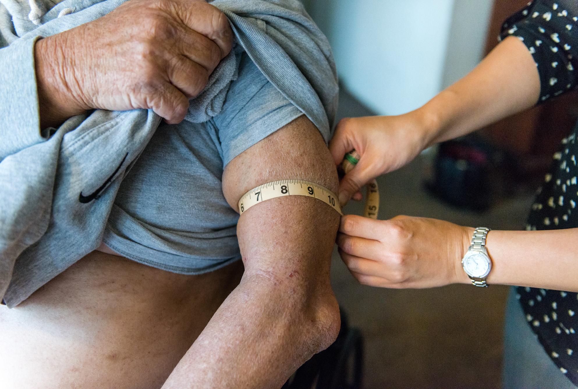 At Gerald Chinchar's home in San Diego, Calif., Nurse Sheri Juan (right) checks his arm for edema that might be a sign that his congestive heart failure is getting worse. (Heidi de Marco/Kaiser Health News)