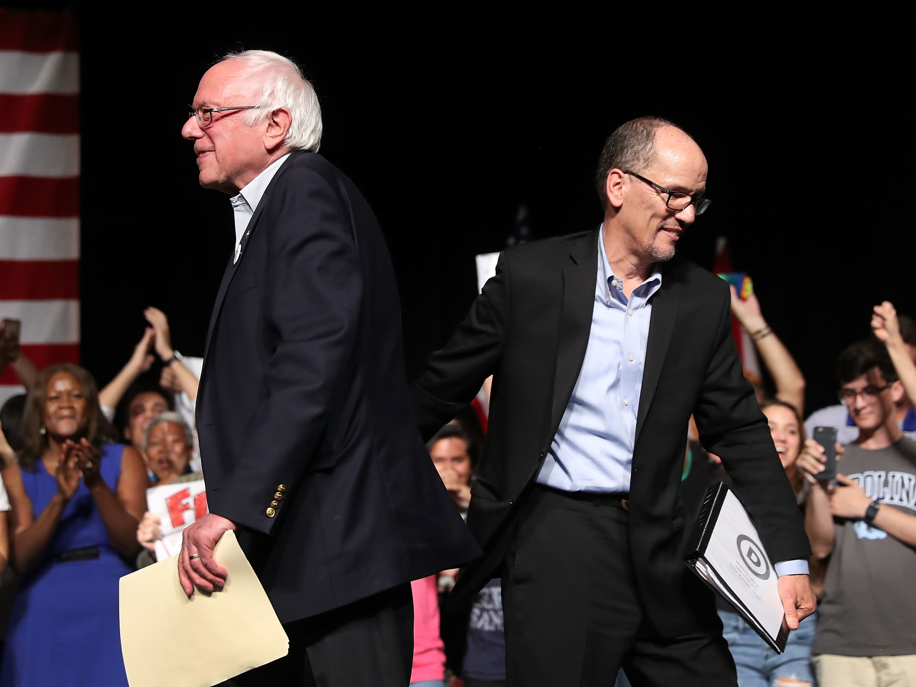Sen. Bernie Sanders and Democratic National Committee Chair Tom Perez walk past each other during their &quot;Come Together and Fight Back&quot; tour at the James L. Knight Center on Wednesday in Miami, Fla. (Getty Images)