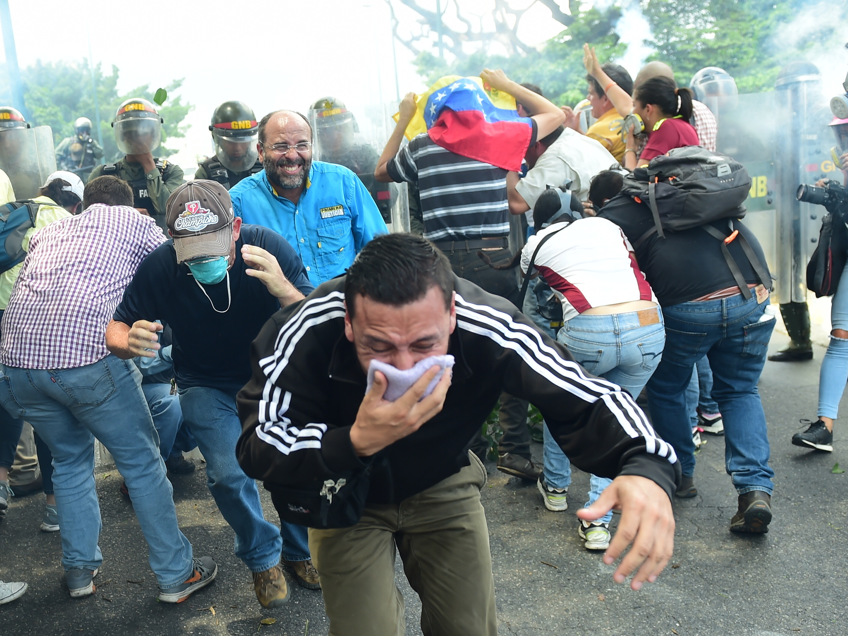 A demonstrator protects his mouth with a cloth as riot police advance on protesters on Wednesday. Security forces fired tear gas and water cannons at protesters during the Caracas rally, while protesters often returned fire with rocks and other objects.