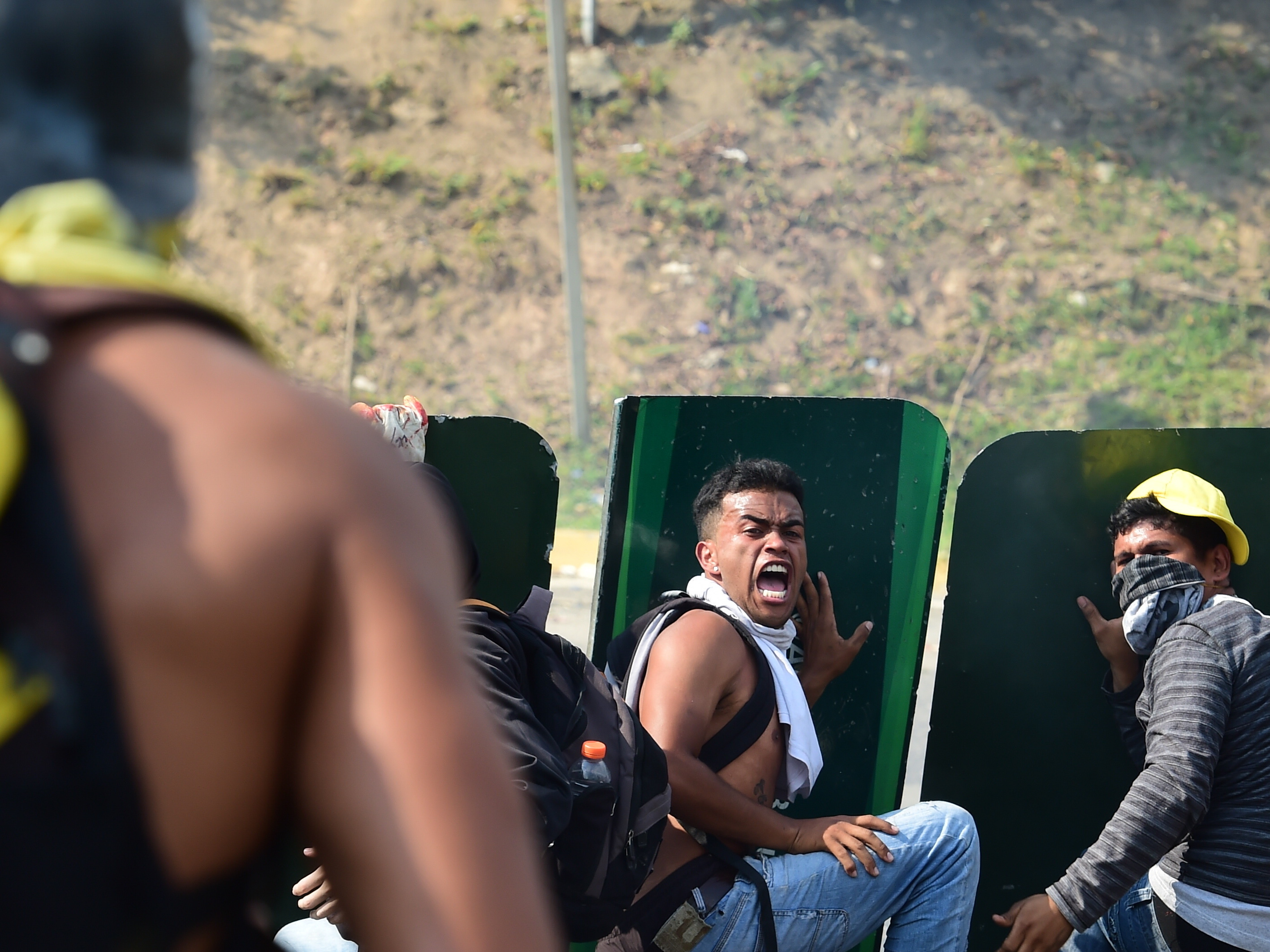 Opposition activists take cover behind advertisement placards during a fight with police in Caracas on Wednesday. More than two dozen people have died since protests against Venezuelan President Nicolas Maduro began to swell roughly a month ago.