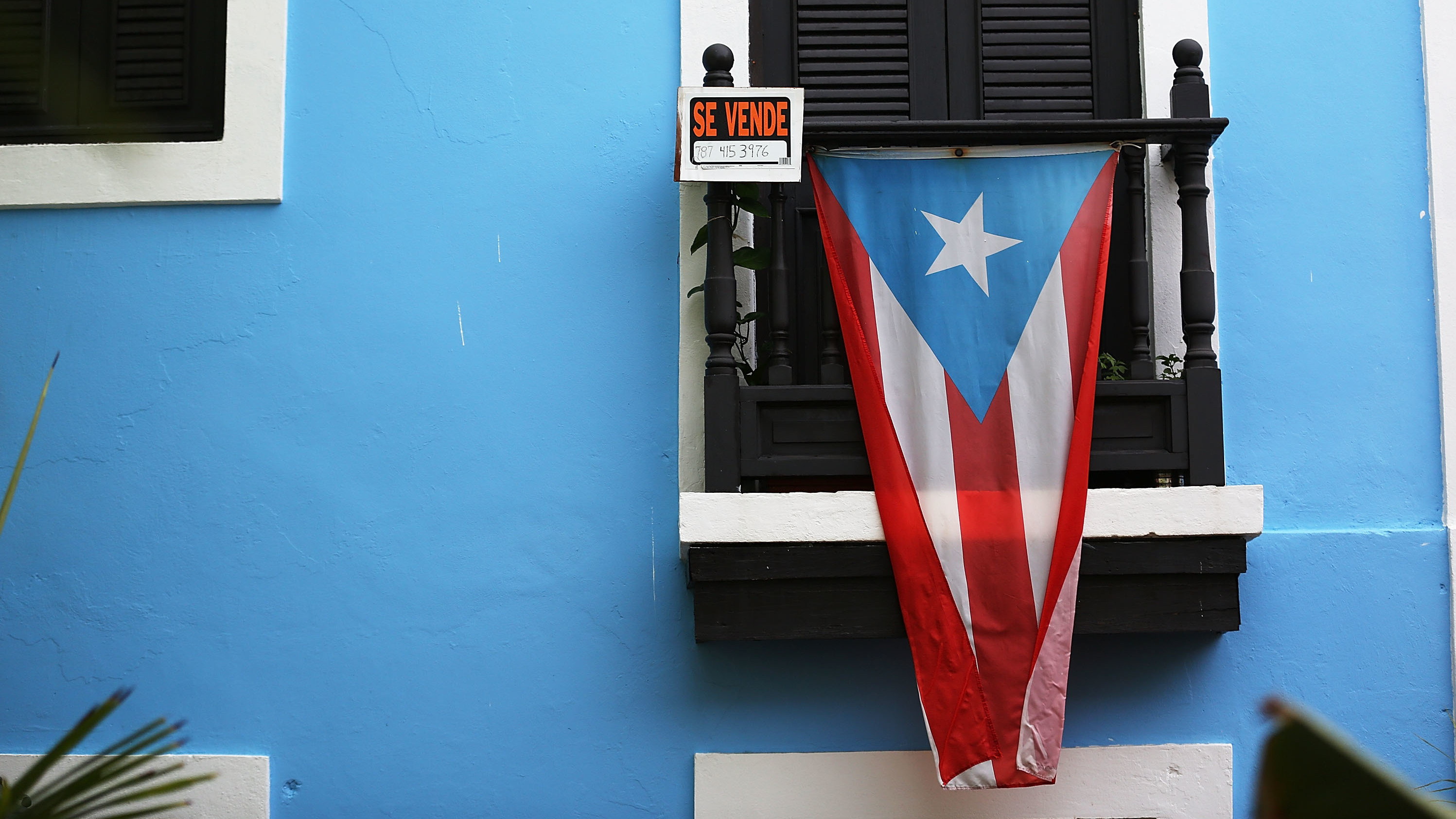 A Puerto Rican flag hangs beside a for-sale sign on a balcony in San Juan in summer 2015. (Getty Images)