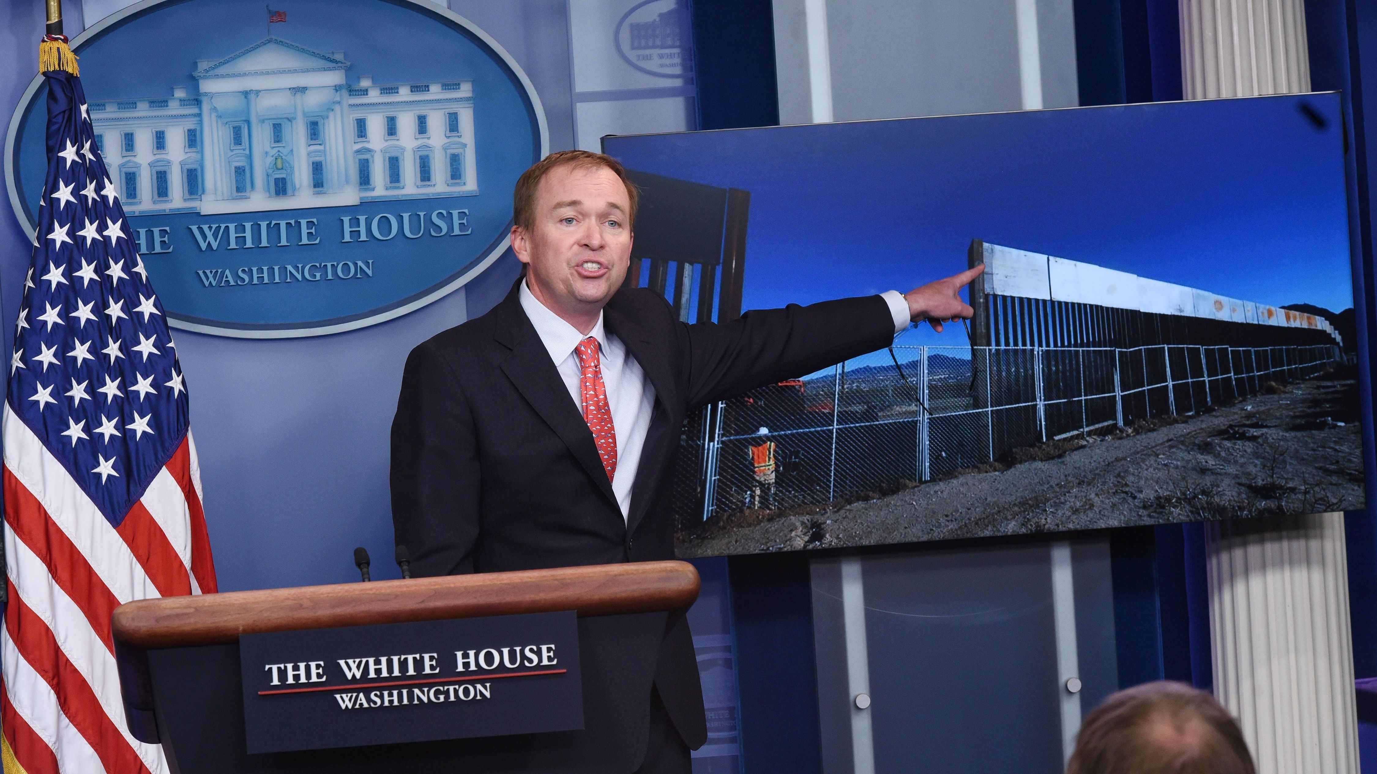 Trump Budget Director Mick Mulvaney points to an image of a border fence, making the case to reporters on Tuesday that there will be a border wall. (AFP via Getty Images)