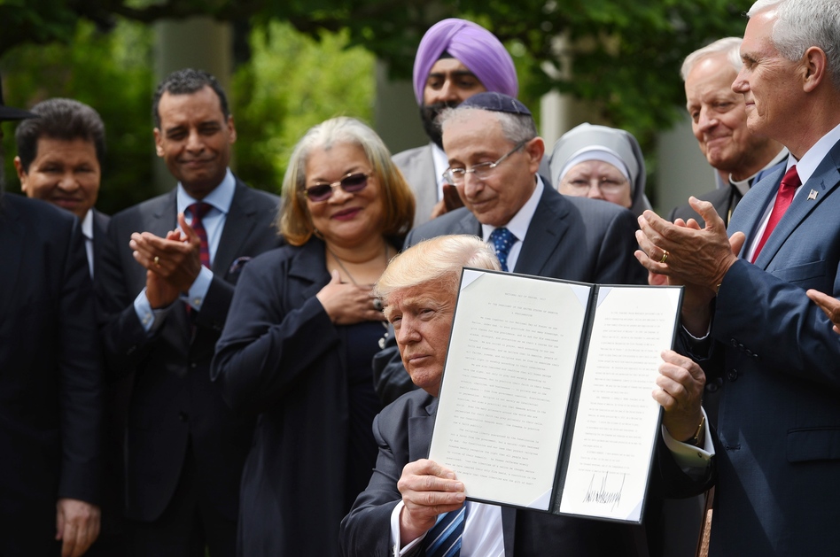 President Trump holds up a proclamation after signing it in the Rose Garden of the White House on Thursday. Trump said he was making it easier for churches and religious groups to take part in politics without risk of losing their tax-exempt status. (Mandel Ngan/AFP/Getty Images)