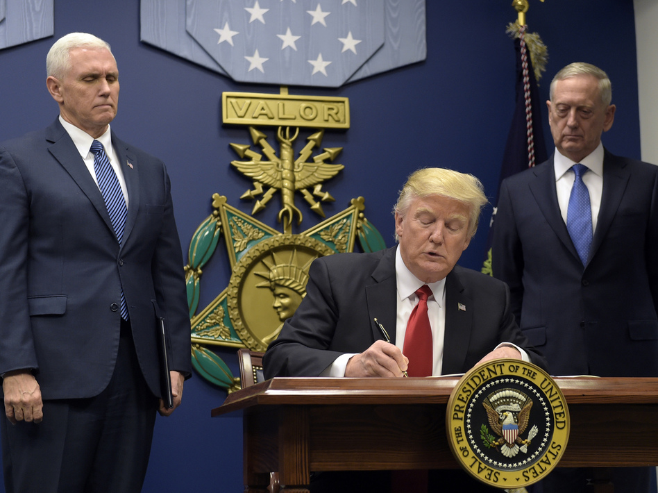 President Trump, with Vice President Pence (left) and Defense Secretary James Mattis (right) watching, signs an executive action on extreme vetting at the Pentagon on Jan. 27. (Susan Walsh/AP)