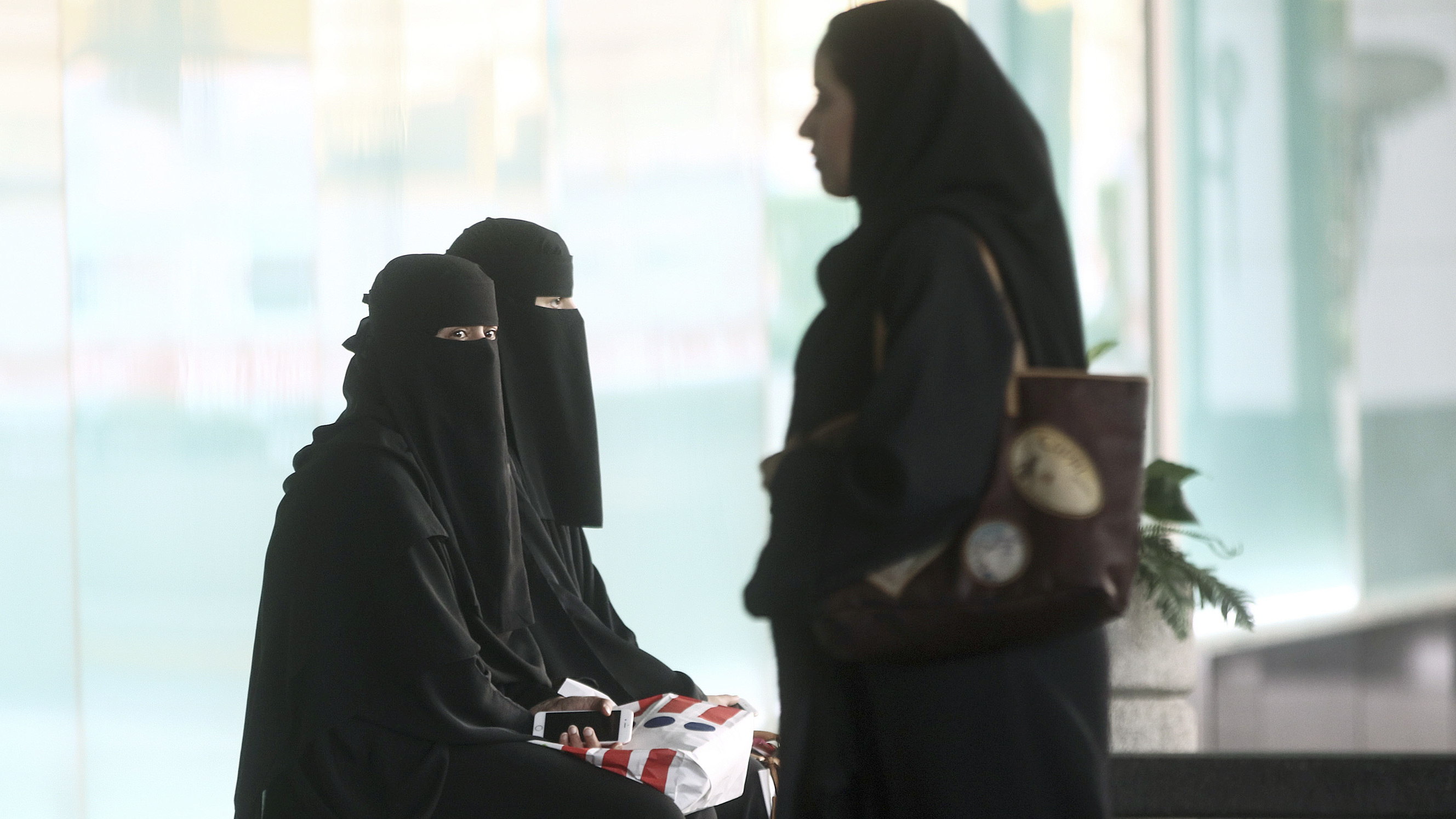 Female shoppers in traditional Saudi Arabian dress wait for their transport outside the Kingdom Centre shopping mall in Riyadh. Women's decision-making abilities are limited by the country's guardianship rules.